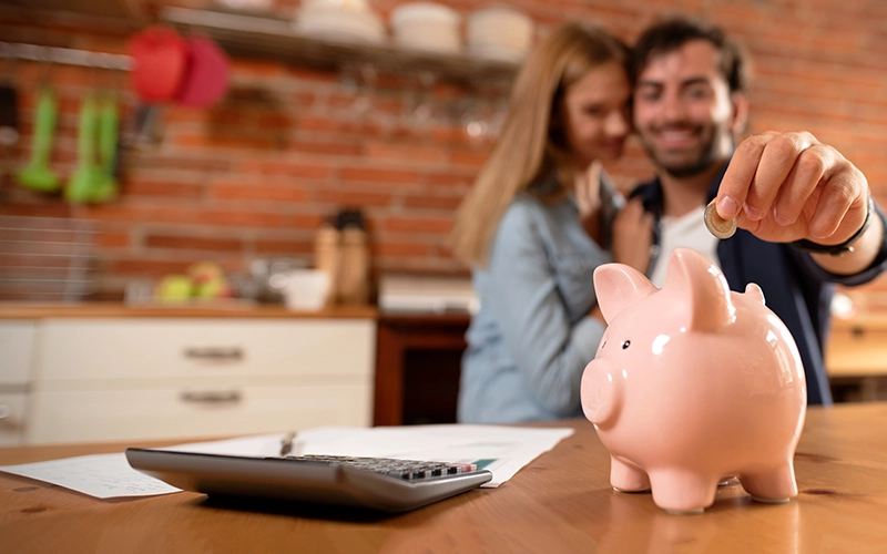 A couple saving money in a piggy bank at home